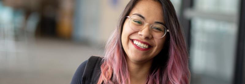 A student smiles in a hallway at a campus