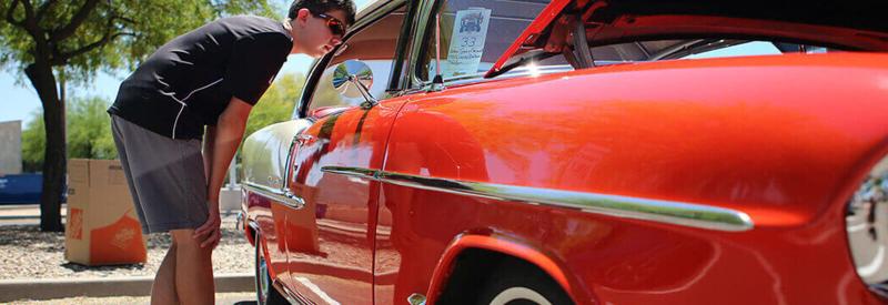 A student looks into the passenger seat of a vintage car at Downtown Campus