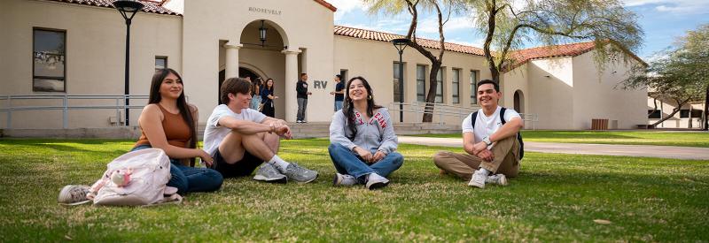Four students sit in a lawn at downtown campus