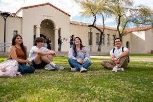 Four students sit in a lawn at downtown campus